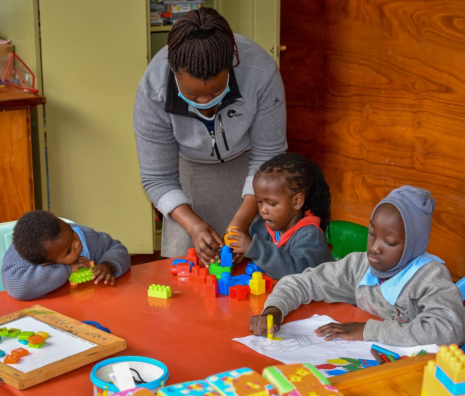 A teacher helping children with learning toys